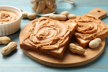 Tasty sandwiches with peanut butter and nuts on light blue wooden table, closeup