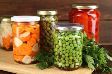 Different pickled products in jars and fresh parsley on table