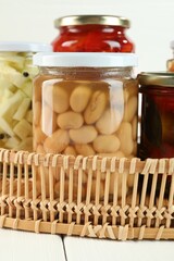 Different pickled products in jars on white wooden table, closeup
