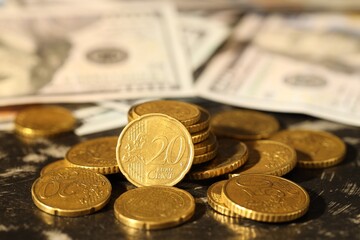Many euro coins and dollar banknotes on dark table, closeup
