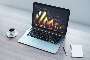 Close up of laptop on wooden desk with coffee cup, supplies and downward forex chart on white wall background. Financial recession and crashing market concept. 3D Rendering.