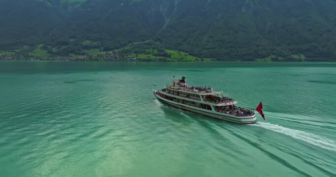 Water transport in Switzerland. Navigating a Swiss Lake. Aerial view steamboat ship on lake Interlaken. Switzerland summer tourism destination. Turquoise blue water. Swiss flag on a passenger ship