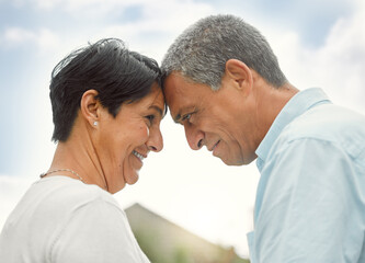 Fototapeta premium Love, forehead touch and mature couple in nature for romance, care or bonding. Smile, man and woman together outdoor for connection, commitment or support for healthy relationship on anniversary date