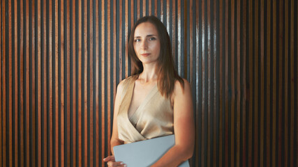 A professional hispanic woman entrepreneur stands confidently against a vertical striped wooden...
