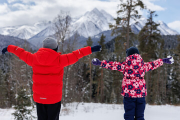 A view from the back of the children against the background of snow-capped mountains and forests.