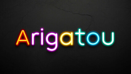 Obraz premium arigatou colorful neon lettering on plain dark black background