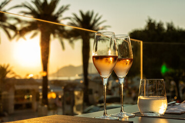 Romantic sunset dinner on the city beach of Croatia. Table for two with wine glasses or drinks in a restaurant with a sea view.