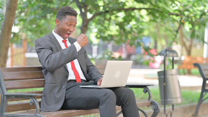 African Businessman Celebrating Success on Laptop in Lap Outdoor
