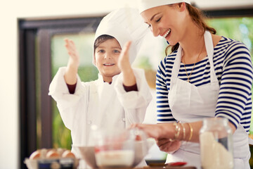 Kitchen, mom and child with a smile, baking and learning with flour, prepare ingredients and happiness. Woman, home and boy with joy, cooking and playful development with recipe and breakfast help