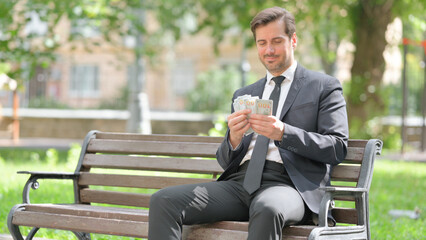 Obraz premium Happy Middle Aged Businessman Counting Money Outdoor