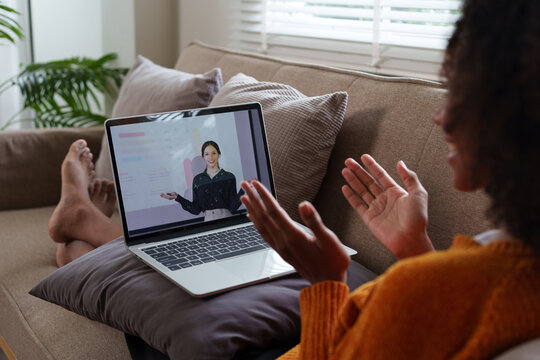 African American female student listens to an online lesson using a laptop, watches a webinar, studies remotely, the teacher and other students are on the laptop screen. E-learning