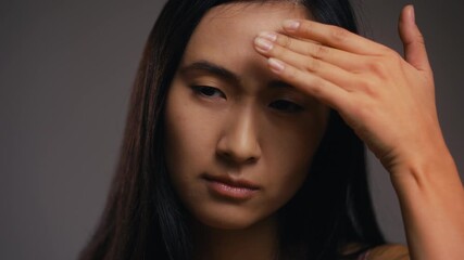 Sad Korean woman touching her face skin, unhappy with first wrinkles, skincare