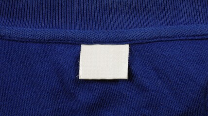 Blank laundry care clothes label on blue t-shirt fabric background.