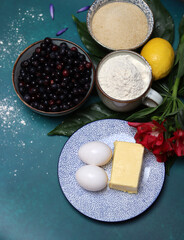 Blueberry pie ingredients on a table. Top view photo of freshly cropped berries, brown sugar, flour, lemon, butter and eggs. Comfort food concept. 