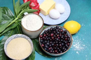 Blueberry pie ingredients on a table. Top view photo of freshly cropped berries, brown sugar, flour, lemon, butter and eggs. Comfort food concept. 