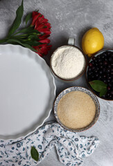 Blueberry pie ingredients on a table. Top view photo of freshly cropped berries, brown sugar, flour, lemon, butter and eggs. Comfort food concept. 