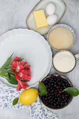 Blueberry pie ingredients on a table. Top view photo of freshly cropped berries, brown sugar, flour, lemon, butter and eggs. Comfort food concept. 