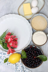 Ingredients for baking pie: flour, eggs, sugar, lemon, blueberries. Light background, top view, copy space