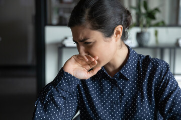 Unhealthy millennial Indian female cough sneeze get infected with coronavirus in office, upset sick young ethnic woman suffer from first respiratory COVID-19 symptoms, corona, healthcare concept