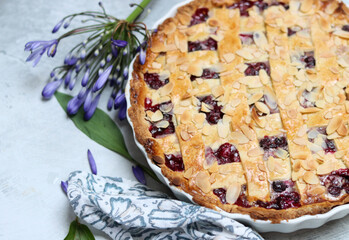 Top view photo of lattice berry pie on a table with summer flowers. Food still life photo. Homemade sweet cake close up. 