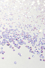 Glittering silver crystal confetti on a blue background. Selective focus.