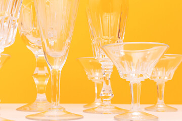 Empty crystal glasses in front of yellow background.