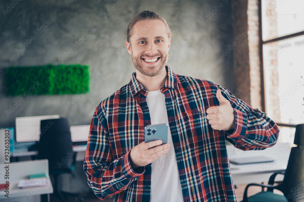 Poster Portrait of successful young man worker smart phone thumb up wear plaid shirt modern loft business center indoors