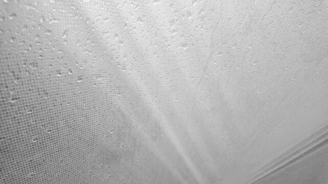 raindrops flow down the silicone durable reinforced rip stop tent awning, light noise and calm. The fabric is waterproof - modern technologies