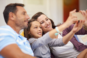 Fototapeta premium Selfie, home and parents with girl on couch, happiness and bonding together in living room. Family, house and mother with father, daughter and picture with break, relax and capture with app and smile