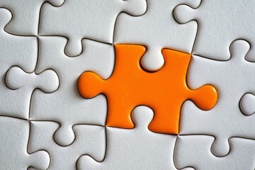 Fototapeta premium Picture of an orange puzzle piece that fits into a white puzzle. Teamwork, solutions, and problem-solving concepts are emphasized