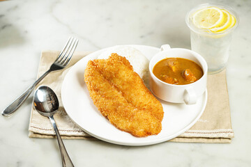 Nostalgic Curry Crispy Fish Fillet Rice with lemonade, fork and spoon, served in dish isolated on napkin side view of asian food