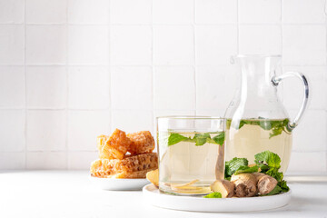 Sweet Ginger Mint Coconut Water Cooler with honey, infused ginger mojito cocktail on white table background copy space