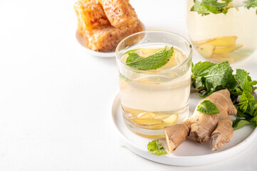 Sweet Ginger Mint Coconut Water Cooler with honey, infused ginger mojito cocktail on white table background copy space