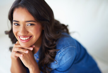 Woman, happy and relax on sofa, portrait and pride on break in living room at modern house. Person, smile and face with confidence in lounge on couch, weekend and chilling at apartment in Colombia