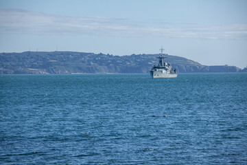 A serene Dublin Bay scene with a boat gently floating on calm waters. The distant cityscape and hills provide a stunning backdrop, reflecting the tranquil beauty of the sea and sky.