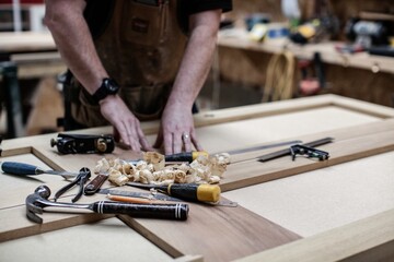 Bespoke joinery showing the carpenter doing all the tasks using the tools like hammer, chisel, drill, steel ruler, glue gun and pencil