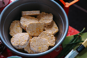 tempe in a bowl is being marinated before being fried