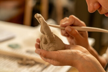 Wooden Tool Refining Clay Sculpture in Pottery Workshop