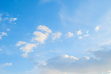 Blue sky landscape with dramatic clouds lit by evening sunset light