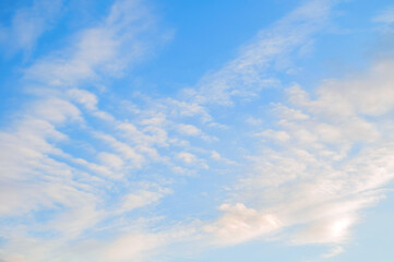 Blue sunset sky landscape with white clouds lit by evening sunset light