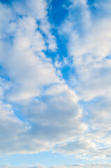 Fototapeta premium Blue cloudy sky background. Blue sky landscape with picturesque sunset clouds lit by evening sunset light - evening blue cloudy sky view