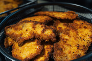 Basket filled with golden-brown, crispy homemade breaded chicken cutlets, freshly cooked and ready to serve. The close-up shot highlights the crunchy texture and delicious appearance of the schnitzel.
