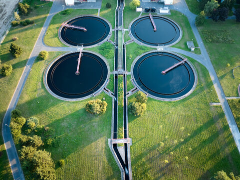 Aerial view of circular sedimentation tanks at a modern wastewater treatment plant. Ideal for: environmental engineering projects, sustainability reports, water industry publications.