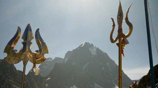 Religious red cloths (chunri) and tridents (trishul), symbols of Lord Shiva, against Kailash Parvat during the Mani Mahesh Kailash Yatra, a Hindu and Buddhist pilgrimage.
