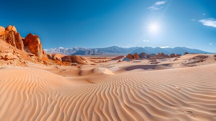 Naklejka premium Stunning Panoramic View of Desert Dunes with Mountains in the Background under a Clear Blue Sky with Bright Sun .