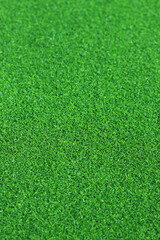 Artificial green grass mat, selective focus. Artificial turf, surface made of synthetic fibers. Green grass texture background. Short artificial grass golf surface