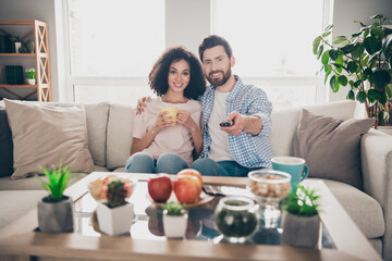 Portrait of two nice young people cuddle watch tv pastime weekend modern apartment indoors