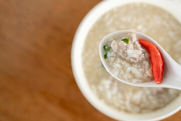 Close-up of a spoonful of rice porridge with pork and chili.
