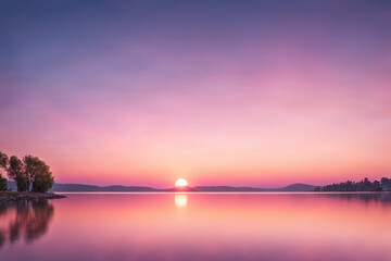 Fototapeta premium Serene Sunset Over Tranquil Lake Surrounded by Mountains and Trees at Dusk