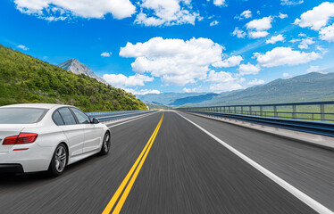 The car is driving along the highway surrounded by picturesque nature.